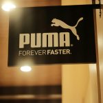 Beranda A glowing Puma store sign with the slogan 'Forever Faster' at night.