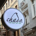 Beranda Chado tea shop signage displayed on an elegant historic street with wrought-iron balconies.